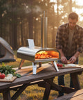 12-Inch Multi-Fuel Outdoor Pizza Oven for Backyard Cooking, Pellet Wood Gas Electric Ready on picnic table, camping scene