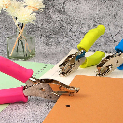 12 Piece Multicolor Single Hole Puncher Set for craft paper with red, yellow, blue grips, shown on desk with notebooks for precise holes