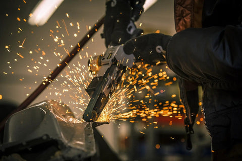 Three Quarter Inch Air Belt Sander Kit with 20.5 Inch Belts in use, sparks flying as it sands metal edge, creating smooth finish.