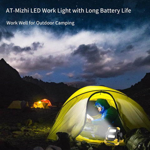 Camper using rechargeable 360 degree rotating LED work light with 2000 lumen brightness inside tent during night camping.