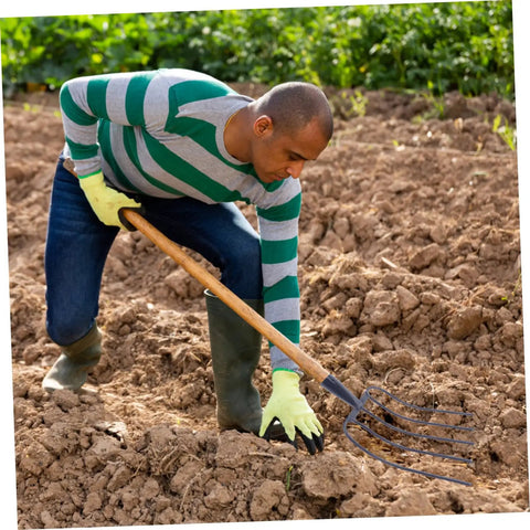Person using Handheld Manure Fork For Farm And Home Use in soil, rugged ergonomic grip, multifunctional yard tool.
