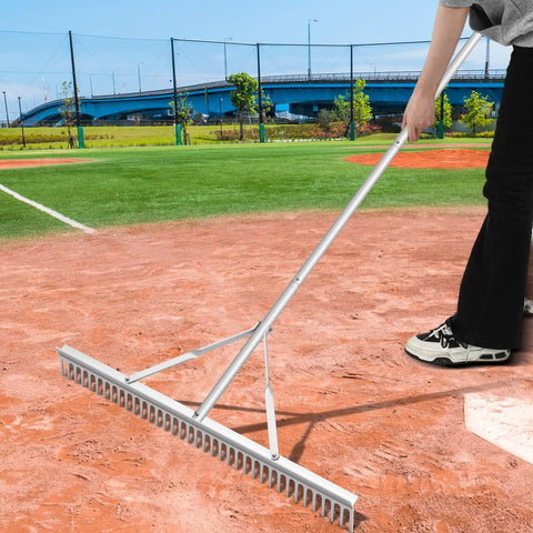 Person using Aluminum Maintenance Rake With Adjustable 66 To 98 Inch Handle, 36 Inch Lawn And Garden Landscape Rake for baseball field prep.
