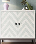 Chevron-patterned cabinet with black knob handles, decorative top items, and wooden flooring background.