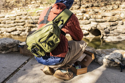 Angler with Mystery Tackle Box Pond Prowler Sling Fishing Lure Kit, Green Sling Pack, hands-free comfort at a creek