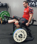 Man using leg extension and curl machine for home or commercial gyms, plate loaded quad and hamstring trainer with adjustable sundial.