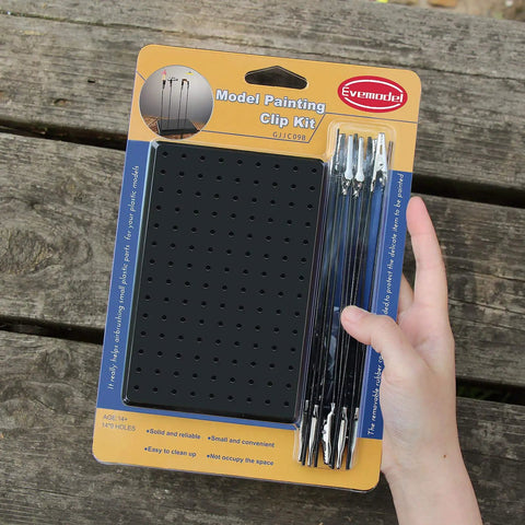 Hand holding packaging of Painting Stand Base And 20 Piece Alligator Clip Stick Set For Airbrush Hobby Model Parts Dope Craft Kit