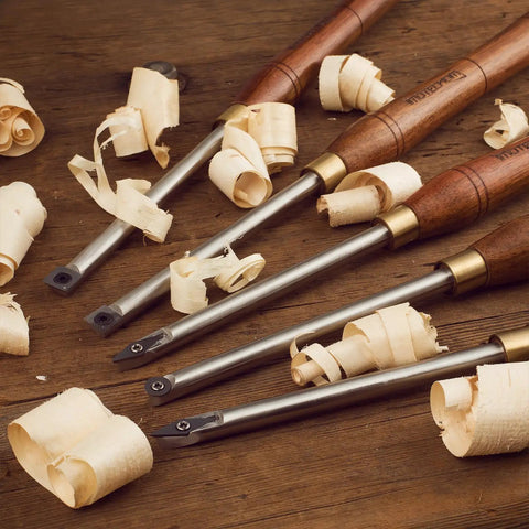 Badass Five Piece Wood Turning Lathe Chisel Set Featuring Rock Solid Tungsten Carbide Tips And Built Tough Square Stainless Handles with wood shavings.