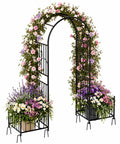 Garden Arbor With Planter Boxes 76 Inch Wide By 86 Inch High Black Metal Archway For Climbing Plants Outdoor Lawn Patio And Backyard Wedding Ceremony Entrance adorned with colorful flowers.