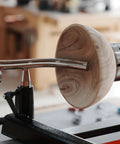 Toolrest set for wood lathe with curved chrome stems supporting a wooden bowl blank on a turning lathe