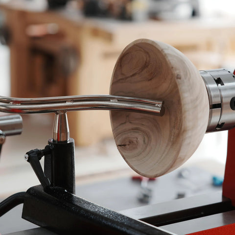 Toolrest set for wood lathe with curved chrome stems supporting a wooden bowl blank on a turning lathe