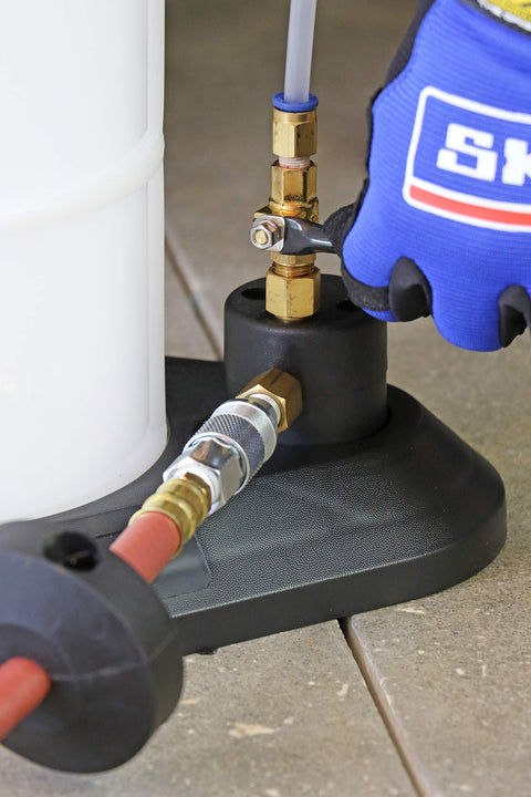 Close-up of Venturi Vacuum Pump Fluid Evacuator pneumatic connections and air shut off valve with glove for operation.