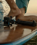 Premium Waterproof Action Camera Bundle With 5.3K60 Video And 27Mp Photos on a surfboard with splashing water.
