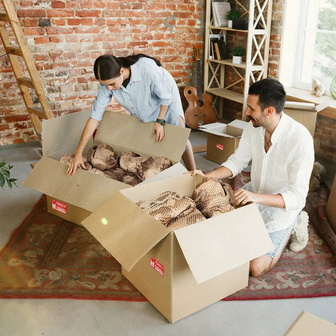 Couple using Top Tier Honeycomb Packing Paper Bubble Wrap Alternative For Moving Supplies Stretchy Kraft Cushion Roll in boxes.