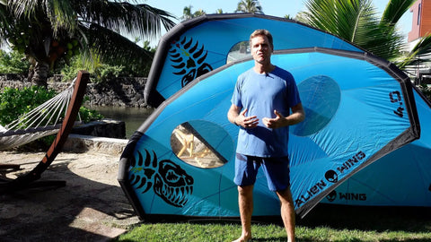 Man standing with Alien Wing 6M High Performance Wind Wing For Foiling And Surfing Lightweight Aerodynamic Rigid Wing in the background.