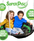 Two children sitting on a foam padding disc swing for two, part of the backyard swing set with multiple play stations for up to five kids.