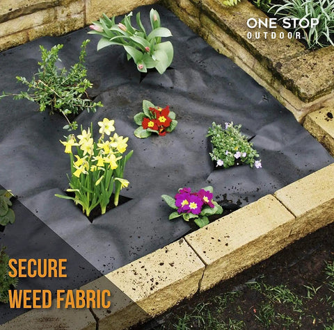 Flower bed with black weed fabric, secured with edging stakes, flowers planted through fabric, brick border visible.
