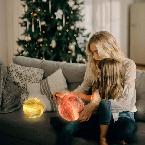 Woman and child with 16-color Lit Galaxy Moon Night Light With Stand And Remote, 3D Printed Moon Lamp on a sofa near Christmas tree.