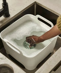 Person using Wash And Drain Kitchen Dish Tub With Handles And Twist Drain Plug 9 Liter Basin For Home RV Or Camping Use.