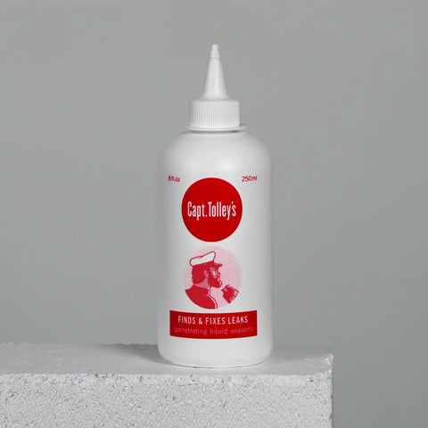 Creeping Crack Cure 8oz Sealant For Hairline Gaps And Cracks bottle on concrete surface, low-viscosity adhesive.