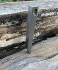Everyday Carry Keychain Pry Bar And Bottle Opener Tool In Stainless Steel standing on wood
