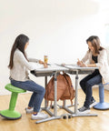 Two people sitting on Sitwell Wobble Stool With Cushion Adjustable Height Active Seating For Movement Perfect For Class Or Home Grassy Green