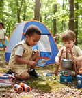 Kids using a magnifying glass and stove beside pop-up tent from Kids Camping Set With Pop Up Tent And Outdoor Gear For Pretend Play Adventures