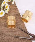 Heavy Duty Brass Pipe Fitting NPT Coupler One Half Inch By One Half Inch Hex Coupler Two Pack on wooden surface with flowers