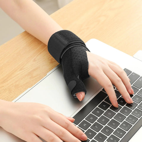 Person wearing Reversible Thumb And Wrist Stabilizer Splint Brace for Trigger Finger Pain Relief while typing on a laptop
