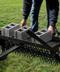 40 Inch Tow Behind Spike Aerator For Lawns With 11 Star Shaped Galvanized Plug Core Tines being adjusted by a person on grass