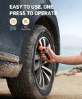 AstroAI orange handheld digital tire pressure gauge being used on a car tire valve