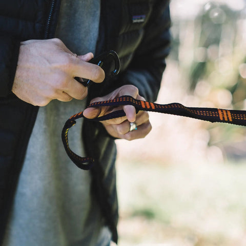 Close-up of hands setting up 10ft Heavy Duty Hammock Straps for Trees with Carabiners, orange loops, knot-free setup, durable gear