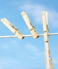 Natural Wood Clothespins 50 Pack Built Different Heavy Duty Wooden Clips With Rust Resistant Springs For Laundry Lines holding fabric outdoors.