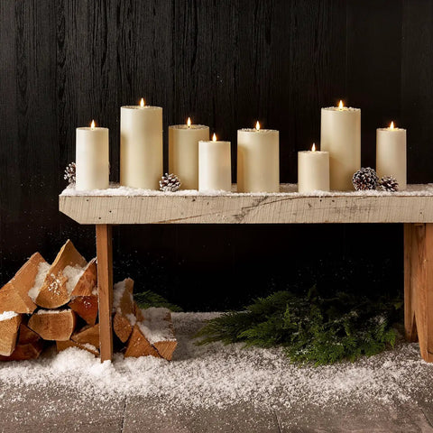 Waterproof Outdoor Flameless Pillar Candles 3 Pack in Ivory Resin, 3x4, 3x5, and 3x6 inches on snowy wooden bench