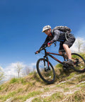 Trail Ready 27.5 Inch Mountain Bike For Men And Women, 21 Speed Shifting, dual disc brakes, riding on grassy trail, sunny day