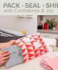 Person packing a parcel in red poly bubble mailer Size 2 small 8.5 x 11 inch pack of 4 on a desk.