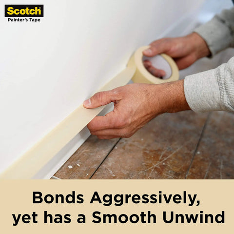 Close-up of hands applying Go To Contractor Grade Tan Masking Tape For General Use And Multi Surface Projects along a wall edge.