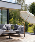 Outdoor lounge area with a patio umbrella stand on a wooden deck with garden view
