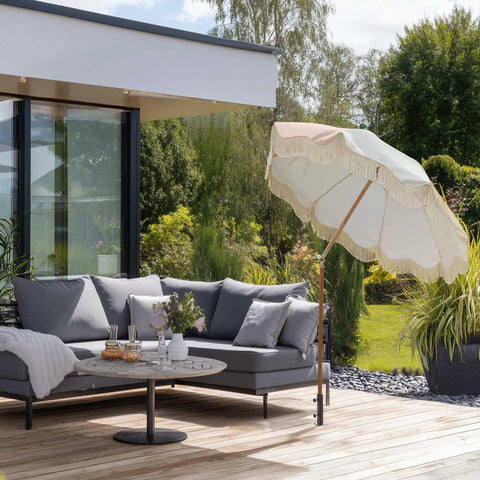 Outdoor lounge area with a patio umbrella stand on a wooden deck with garden view