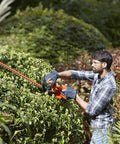 Man using Heavy Duty Electric Hedge Trimmer With 420 Watt Motor And 45CM Cutting Blade For Fast Yard Cleanup on thick hedge.