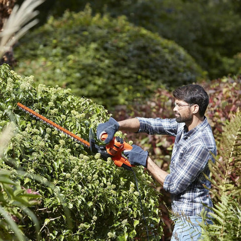 Man using Heavy Duty Electric Hedge Trimmer With 420 Watt Motor And 45CM Cutting Blade For Fast Yard Cleanup on thick hedge.