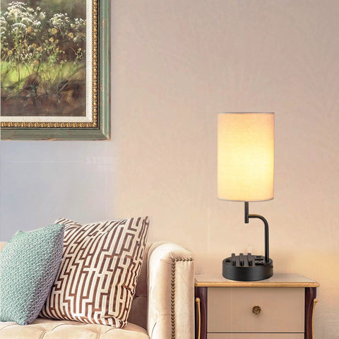 Bedside table lamp with three USB ports and AC outlet cream, modern desk lamp with phone stands, in living room setting.