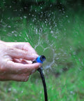 Hands adjusting the Adjustable 360 Degree Drip Emitters Sprayer For One Quarter Inch Tubing with water spray in garden