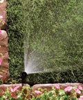 Top Notch Quarter Circle Spray Nozzle Covers Eight To Fifteen Feet in action, spraying water on lush green grass and flowers.