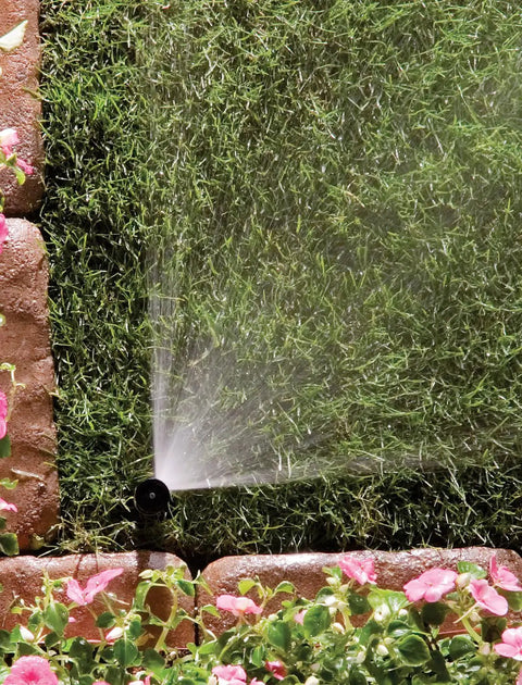Top Notch Quarter Circle Spray Nozzle Covers Eight To Fifteen Feet in action, spraying water on lush green grass and flowers.