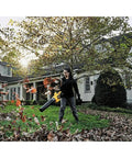 Person using 60V Max FlexVolt Cordless Handheld Leaf Blower 125 MPH Air Speed 600 CFM Airflow Tool Only in yard with fallen leaves