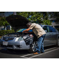 Mechanic using Heavy-Duty 24 By 34 Inch Black Plush Vinyl Fender Cover Pad for Auto Repair And Maintenance on silver car.