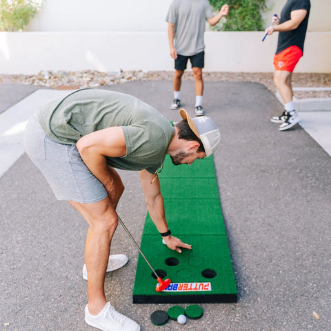 People playing with Backyard 12 Ft Putting Green Golf Game Set With 2 Putters 2 Balls Hole Covers Foldable Mat in outdoor setting