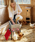 Woman filling Top Shelf Metal Chicken Feeder With 30 Pound Capacity And Six Accessible Ports while chickens feed nearby.