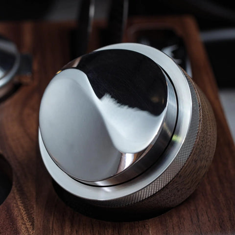 Close-up of Walnut 58.35mm Espresso Distribution Tool, Adjustable Depth, Stainless Steel Leveler for 58mm Portafilters on a wooden surface.