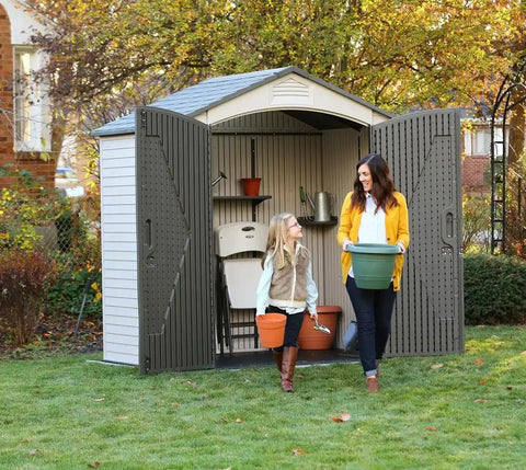 Built Tough Outdoor Storage Shed 7 x 4.5 Ft With Steel Reinforced Construction in garden with two people carrying pots